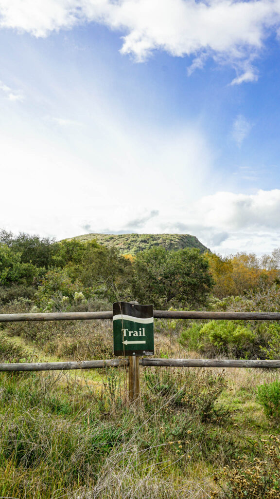 A sign that says "Trail" and shows you the way along Lake Calavera Trail