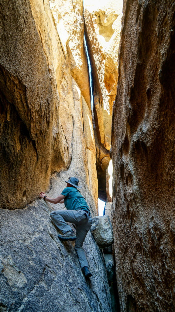 Alex climbing higher up the boulders at the Hall of Horrors in Joshua Tree
